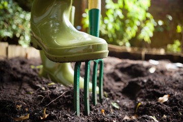 Close-up low section of woman standing with fork on dirt