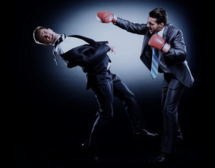 Two young businessman boxing againts dark background