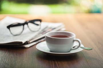 Newspaper reading glasses coffee cup.