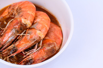 Close up view of prawns on curry noodles in a white ceramic bowl.  White background.