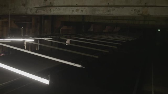 4k shot of white fluorescent lighting turn on and off and reflecting in the water or puddle in industrial building. Many neon lights blinking and flashing on the ceiling.