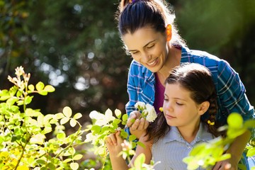 Smiling woman with daughter smelling white roses