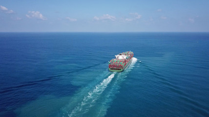 Huge large mega container ship sails on open water fully loaded with containers and cargo - aerial view