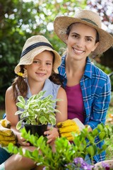 Portrait of smiling mother and daughter with potted plants