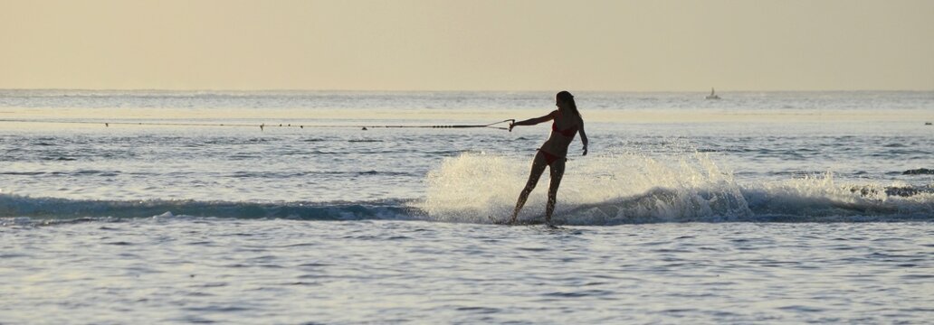 A girl wakeboarding at sunset