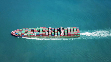 Huge large mega container ship sails on open water fully loaded with containers and cargo - aerial view