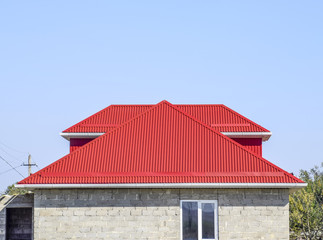 Red corrugated roof. House of cinder block. House with plastic windows and roof of corrugated sheet
