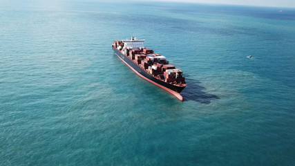 Huge large mega container ship sails on open water fully loaded with containers and cargo - aerial view