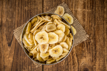 Portion of Dried Banana Chips on wooden background, selective focus
