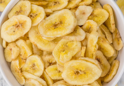 Portion of Dried Banana Chips on wooden background, selective focus