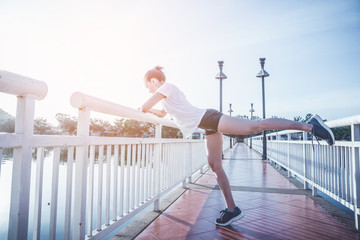 Healthy woman doing exercises and warm up before running and jogging on bridge at morning 