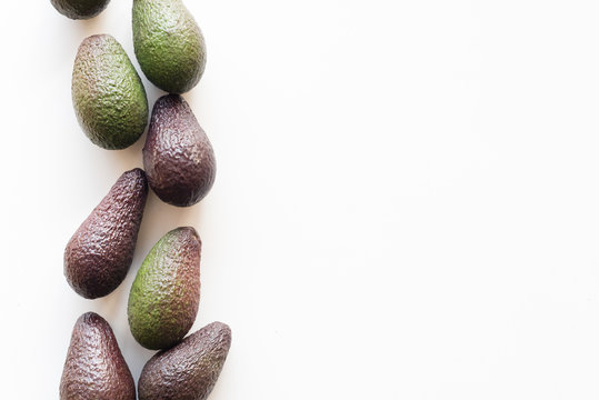 High Angle View Of Organic Green And Black Hass Avocados On White Table Background With Copy Space