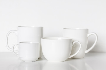 White porcelain mugs, different size and design,  tea and coffee cups, clean dishes mock up