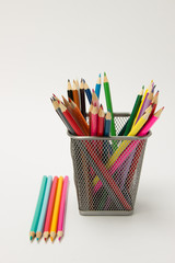A group of colored pencils in a writing-glass on a white background