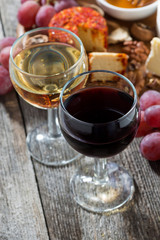glass of white and red wines, appetizers on a wooden table, vertical, top view