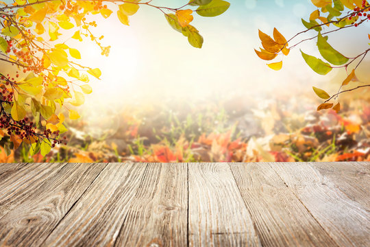Wooden table with autumn leaves background