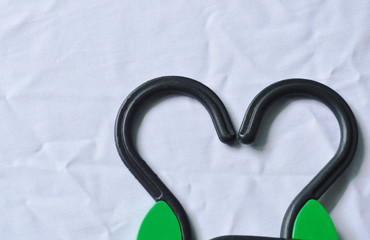 black plastic clothes hanger arranging heart shape on white fabric background