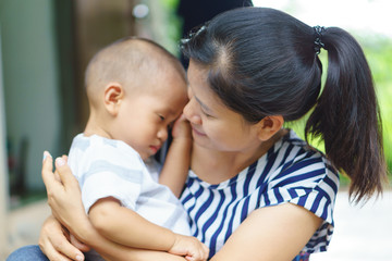 Sleepy Asian baby being held by his mother