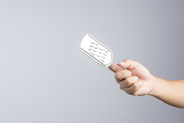 Hand holding grater for peeling fruits and vegetables