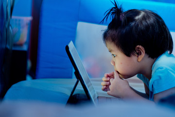 asian children watching tablet  / playing phone and looking at cartoon / kid play tablet
