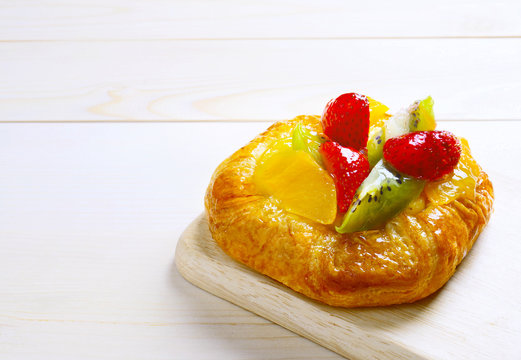 Danish Pastry with mixed fruit on brown wooden background with copy space. Selective focus.