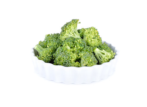 portion cut fresh broccoli in white bowl and on white background