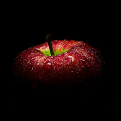 Water droplet on glossy surface of red apple on black background