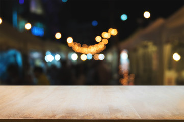 empty wood table in front of blurred montage night market bokeh background