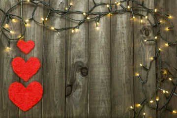 Festive frame on wooden boards, with hearts and garland.