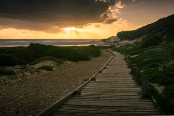 The boardwalk leads to the beach and the setting sun