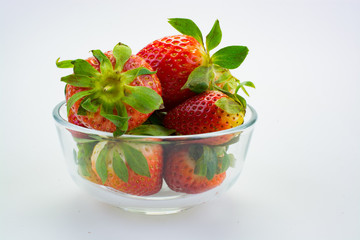 Strawberries in glass bowl against white background.