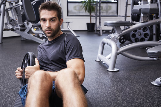 Serious sit ups guy working out in gym, portrait