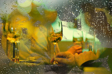 View from outside rainy day a restaurant window at a table with wine glasses