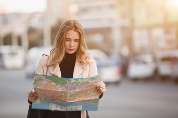 Tourist woman traveller looking to map standing in european city street