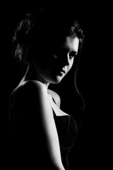 beautiful sad young woman on black background looking at camera, monochrome