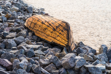 Old wooden boat lying on stones closeup