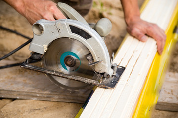 worker saws a wooden plank at a construction site