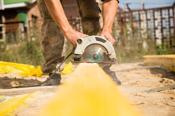 worker saws a wooden plank at a construction site