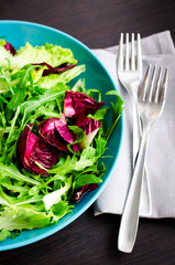 Fresh summer green salad mix on a wooden table