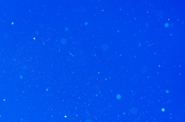 Falling snow over blue background in free space