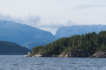 Summer Norwegian landscape with a lighthouse on the shore of the fjord
