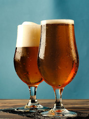 Two mugs of beer on a blue background.