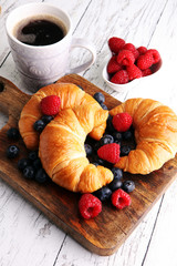 Delicious breakfast with fresh croissants and ripe berries on ta