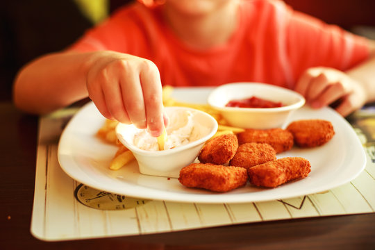 boy eating fast food in a cafe. the child eating french fries with nuggets