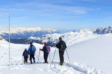 Group of people hiking on snowshoes and mountain snow panorama with blue sky in Stubai Alps, Austria