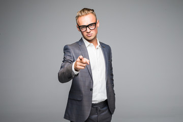 young business man in glasses pointing and looking at the camera. on a gray background