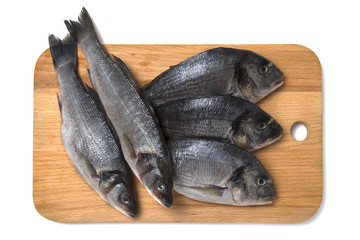 Fresh dorado and sea bass fish on wooden cutting board