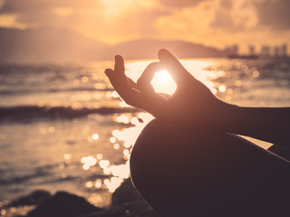 Yoga concept.  Silhouette woman hand practicing lotus pose on the beach at sunset.
