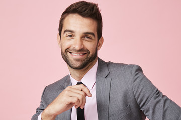Happy businessman in grey suit in pink studio, portrait