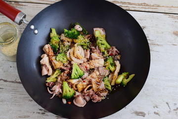 Wok fried squid with broccoli, soy sauce and sesami seeds